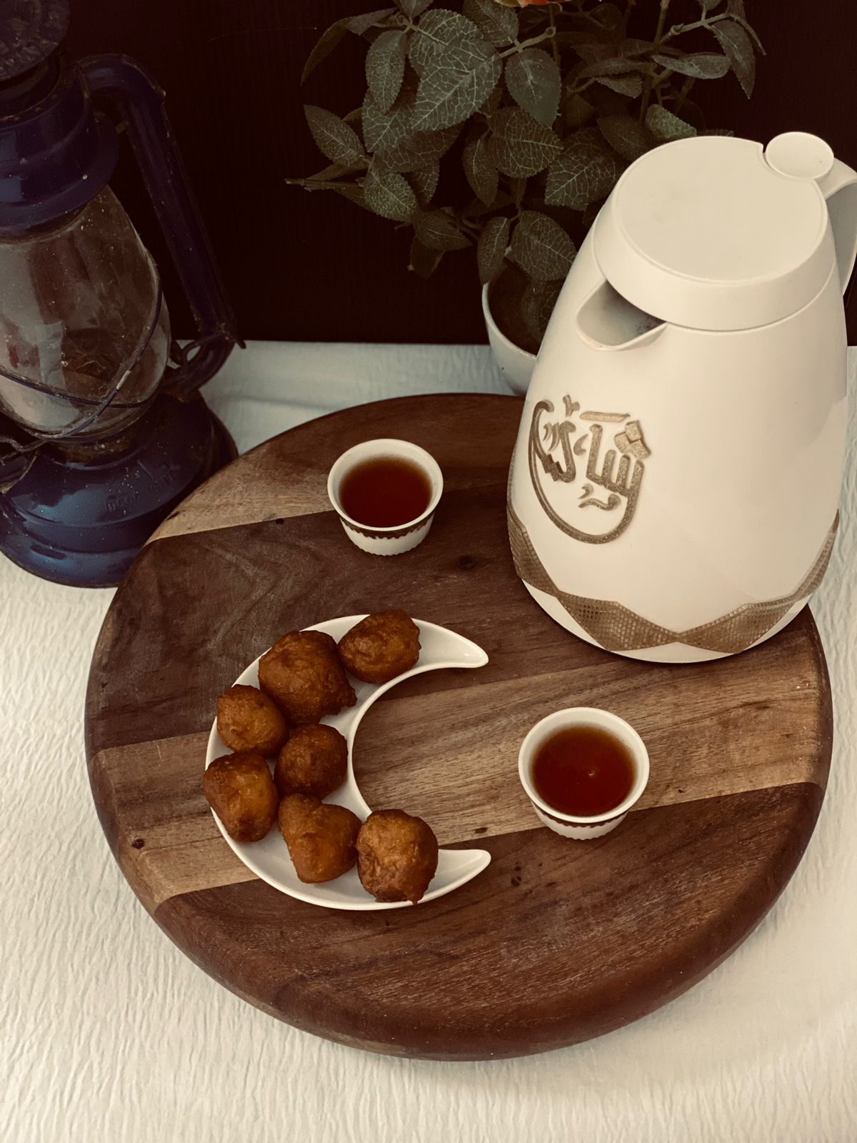 Luqaimat dumplings beside cups and a serving pot